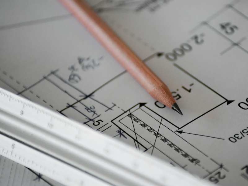 Crayon posé sur un plan de construction à côté d'une règle d'architecte